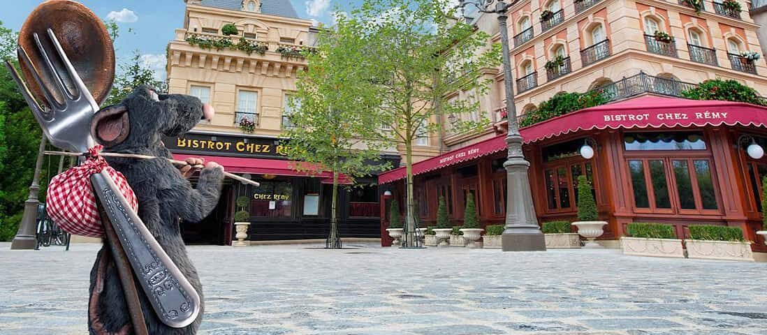 Ratatouille, une souris avec un sac d'ustensiles, debout dans une rue pavée.