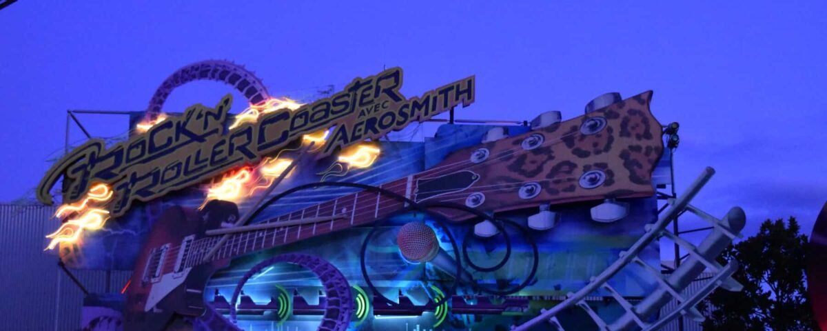 Enseigne lumineuse pour le "Rock'n Roller Coaster avec Aerosmith" comportant une piste de montagnes russes et une guitare au crépuscule.