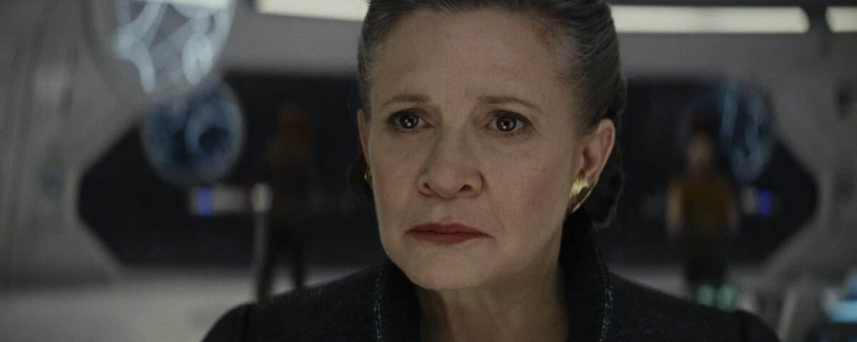 Carrie Fisher dans le rôle de la princesse Leia Organa, l'air inquiète, dans un centre de commandement futuriste avec des accents bleus et des figures floues en arrière-plan.