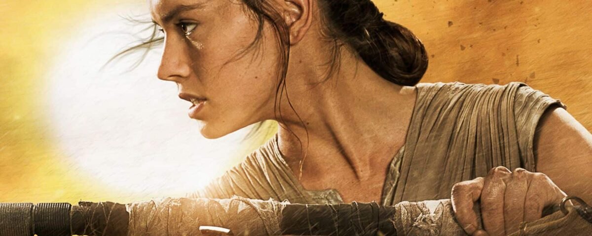 Un gros plan de Rey de Star Wars, interprétée par Daisy Ridley, regardant intensément sur le côté, les cheveux attachés en arrière et tenant un bâton, sur un fond lumineux et ensoleillé.