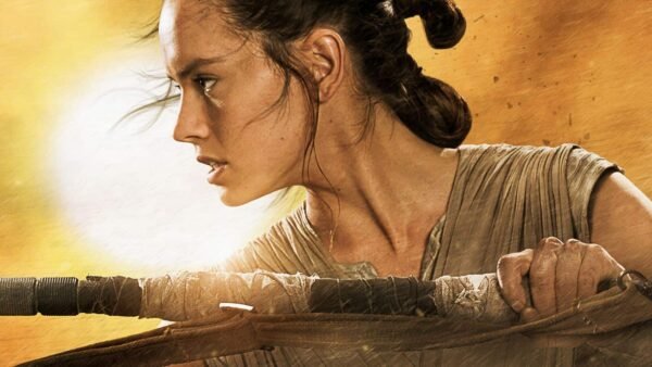 Un gros plan de Rey de Star Wars, interprétée par Daisy Ridley, regardant intensément sur le côté, les cheveux attachés en arrière et tenant un bâton, sur un fond lumineux et ensoleillé.