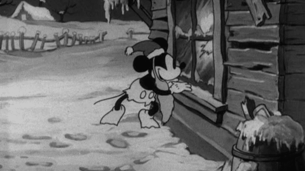 Animation en noir et blanc de Mickey Père Noël portant un foulard, l'air plein d'espoir devant une cabane enneigée, avec des empreintes de pas menant à la porte.