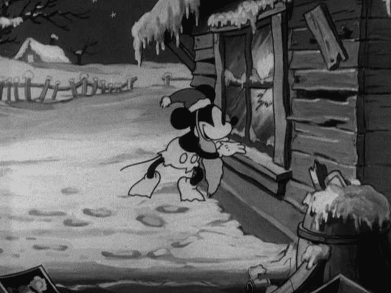 Animation en noir et blanc de Mickey Père Noël portant un foulard, l'air plein d'espoir devant une cabane enneigée, avec des empreintes de pas menant à la porte.