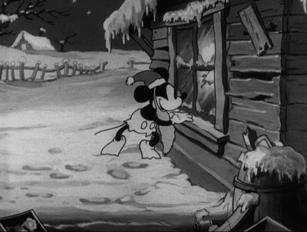 Animation en noir et blanc de Mickey Père Noël portant un foulard, l'air plein d'espoir devant une cabane enneigée, avec des empreintes de pas menant à la porte.