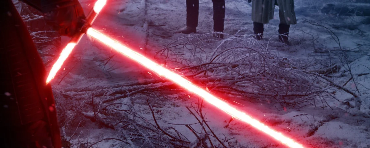 Un laser sabre crossguard rouge brillant se trouve sur un sol couvert de givre dans une forêt enneigée, avec deux personnages sombres debout en arrière-plan.