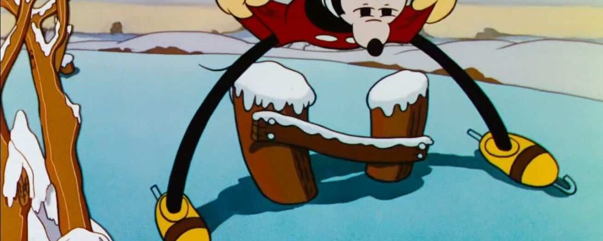 Mickey Mouse patine sur la glace, jambes écartées et bras tendus pour l'équilibre, avec un paysage hivernal en arrière-plan. La neige recouvre une partie du sol et des branches d'arbres.