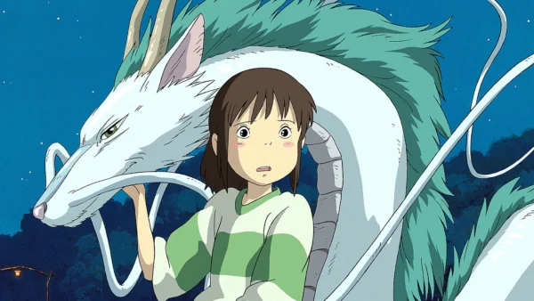Une scène d'un film de Miyazaki montrant une jeune fille vêtue d'un haut vert et blanc, l'air surprise à côté d'une grande créature mythique blanche avec de longues moustaches et des dents pointues sur un ciel nocturne.