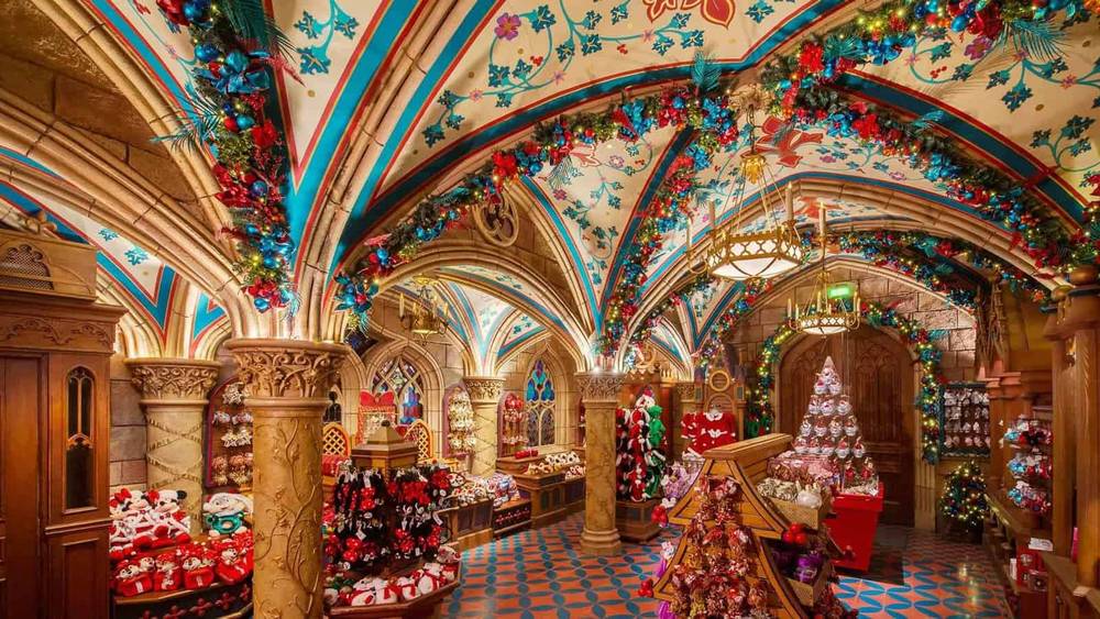 Une boutique du château finement décorée sur le thème de Noël, avec des motifs de plafond vibrants, des arcades et des étagères remplies de décorations et de cadeaux festifs.