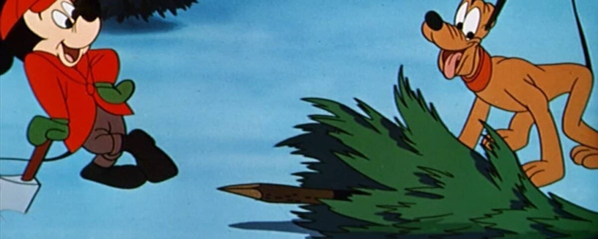 Mickey Mouse, portant un chapeau rouge et des mitaines vertes, se tient à côté d'un sapin de Noël tombé, tandis que Dingo, tenant le sapin, regarde avec une expression enjouée dans un décor enneigé.