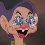 Une image de dessin animé de Simplet, l'un des sept nains, souriant largement avec des lunettes scintillantes serties de diamants sur les yeux. Ses yeux sont écarquillés d'excitation et il porte un chapeau violet.