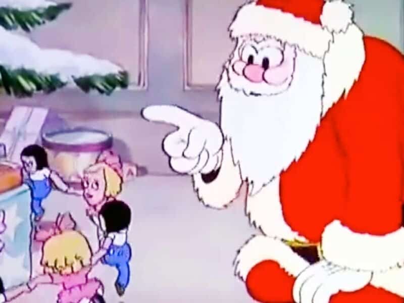 Le Père Noël, dans son costume rouge traditionnel, interagit de manière animée avec un groupe d'enfants excités dans une pièce confortable et décorée de façon festive avec un arbre de Noël.