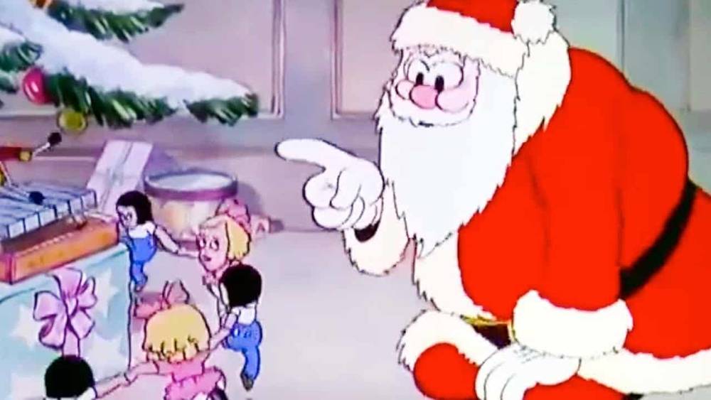 Le Père Noël, dans son costume rouge traditionnel, interagit de manière animée avec un groupe d'enfants excités dans une pièce confortable et décorée de façon festive avec un arbre de Noël.