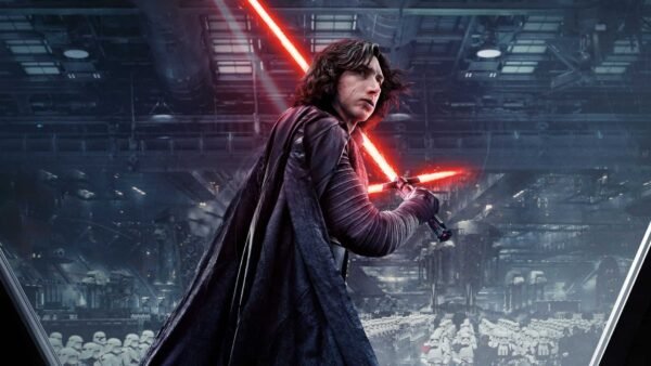 Kylo Ren se tient bien en vue avec un sabre laser rouge allumé, vêtu de robes sombres, à l'intérieur d'un hangar de vaisseau spatial rempli de stormtroopers en arrière-plan.
