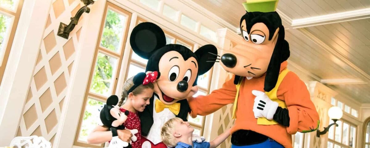 Une interaction joyeuse avec une jeune fille et un garçon rencontrant Mickey Mouse et Dingo à Disneyland Paris, les enfants portant des tenues sur le thème Disney.