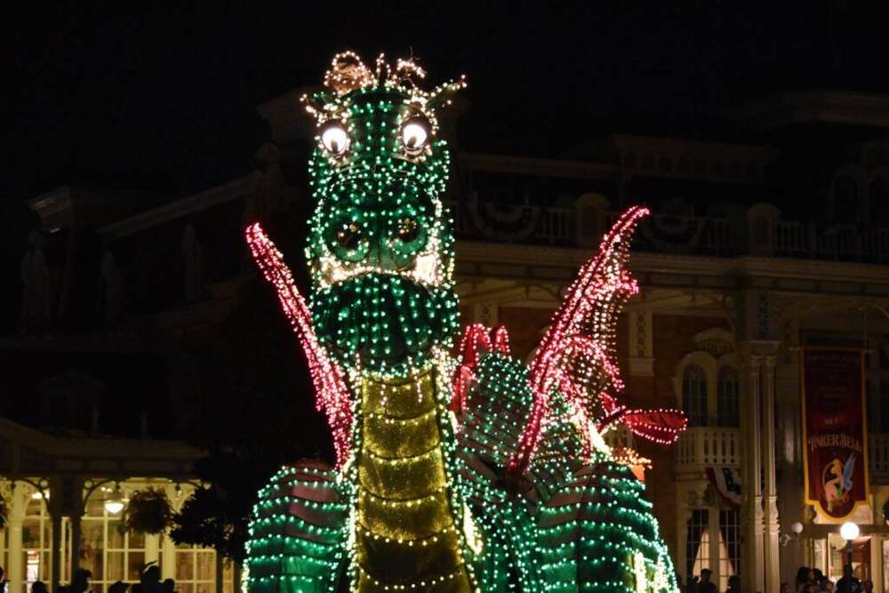 Un dragon est illuminé la nuit devant un immeuble du plus grand parc Disney.