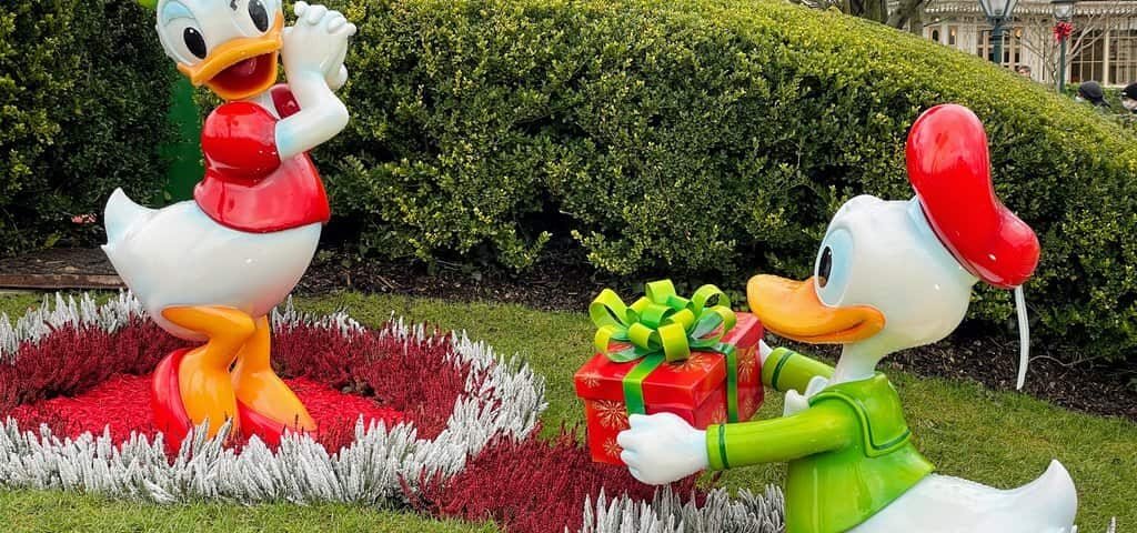Une paire de figurines de Donald Duck dans un jardin, servant d'adorables souvenirs de Noël aux enfants visitant Disneyland Paris.
