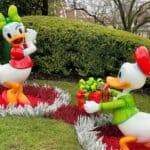Une paire de figurines de Donald Duck dans un jardin, servant d'adorables souvenirs de Noël aux enfants visitant Disneyland Paris.