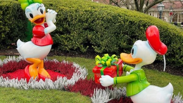 Une paire de figurines de Donald Duck dans un jardin, servant d'adorables souvenirs de Noël aux enfants visitant Disneyland Paris.