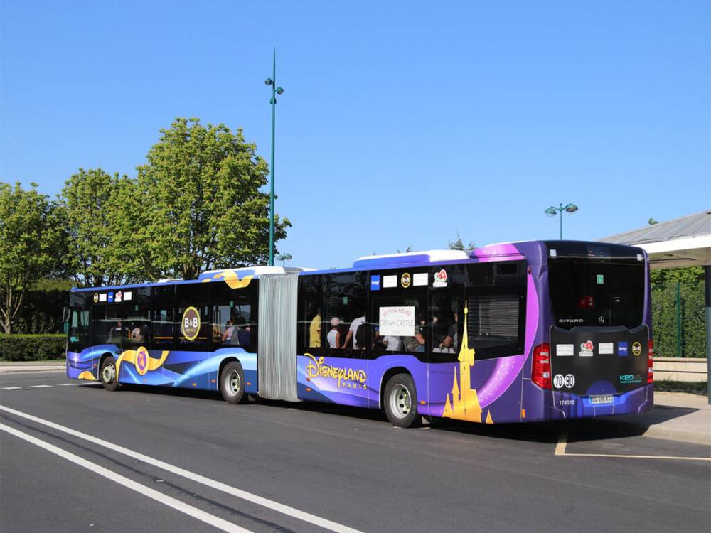 Un bus bleu et violet garé à un arrêt de bus près de l'hôtel Disneyland Paris.