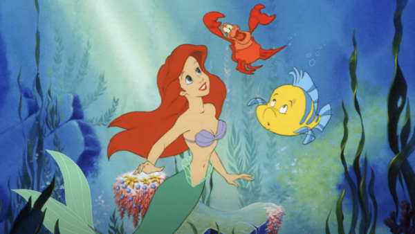 Ariel, la sirène rousse de "La Petite Sirène" de Disney, nage sous l'eau accompagnée de ses amis, le crabe Sébastien et le poisson Flet, sur fond de plantes océaniques et