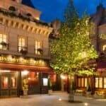 Une charmante vue nocturne du "Bistrot Chez Rémy", l'une des principales attractions de Disneyland Paris, avec des intérieurs chaleureusement éclairés et des lampadaires ornés, entouré d'arbres verts luxuriants dans un