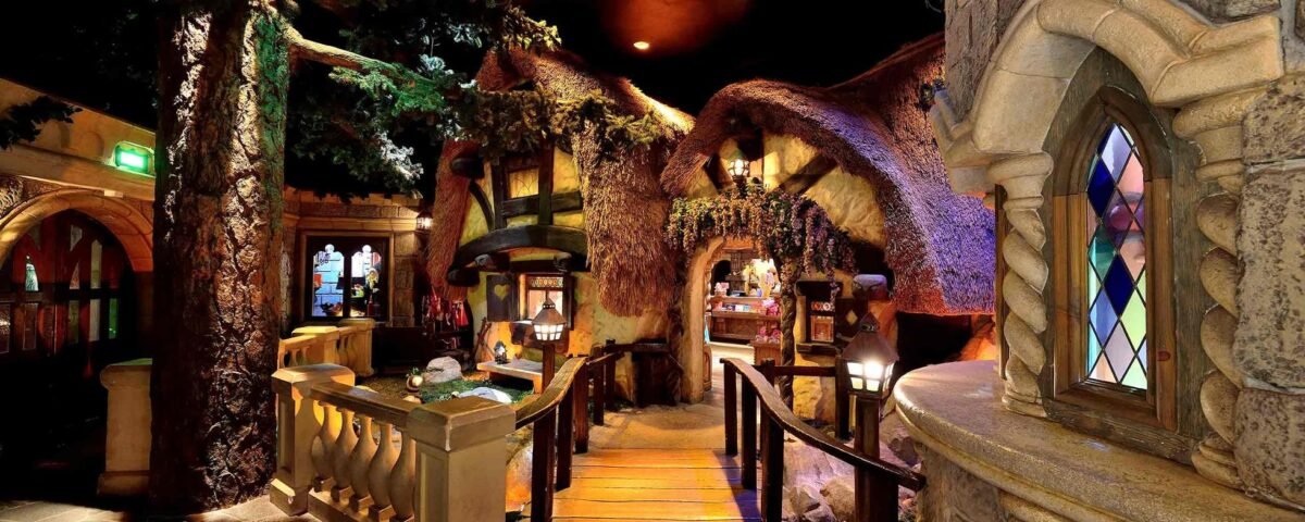 Un intérieur fantaisiste représentant une salle au thème fantastique inspirée de Disneyland Paris, avec des structures en forme d'arbre, des toits couverts de mousse et une allée pavée menant à un bar aux allures de château avec des vitraux