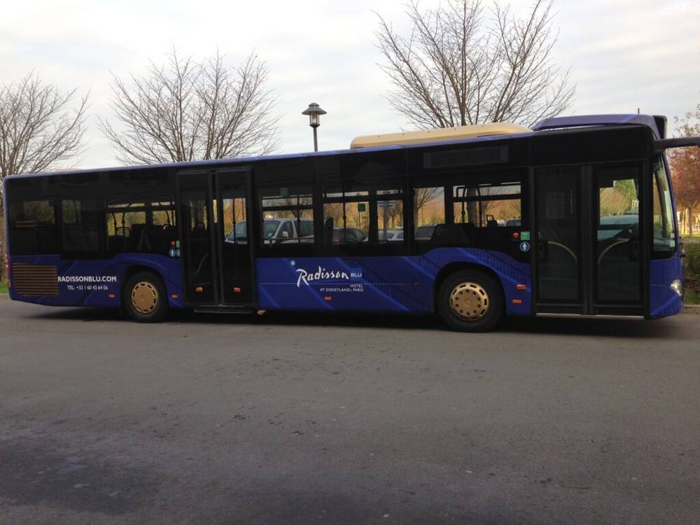 Un bus bleu garé dans un parking proche de Disneyland Paris.