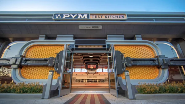 L'entrée de la cuisine PYM à Disneyland Paris, présentant un design élaboré avec des poignées circulaires surdimensionnées qui ressemblent à des boutons de réglage et une façade métallique moderne.
