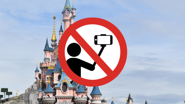 Un panneau d'interdiction sur Disneyland Paris indiquant qu'aucun selfie ou perche à selfie n'est autorisé. Le panneau représente une caméra avec une barre oblique et une personne assise, également barrée.
