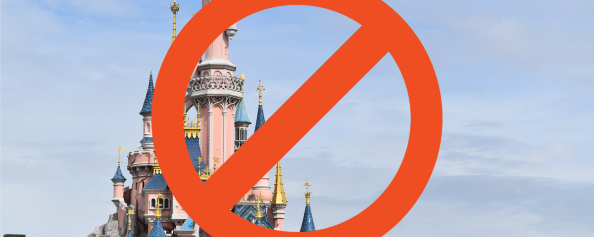 Un panneau d'interdiction rouge recouvre une photo de Disneyland Paris avec des flèches colorées sous un ciel bleu avec des nuages.