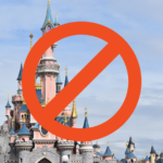 Un panneau d'interdiction rouge recouvre une photo de Disneyland Paris avec des flèches colorées sous un ciel bleu avec des nuages.