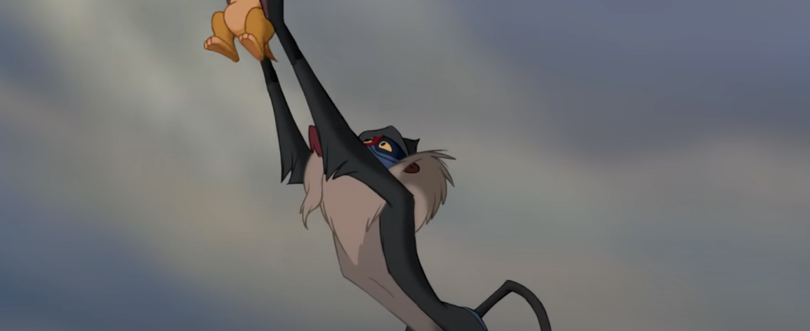 Une scène de "Le Roi Lion" montrant Rafiki tenant Simba en l'air sur Pride Rock sous un ciel dramatique.