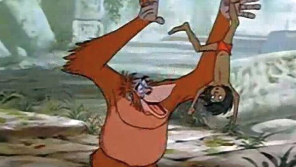 Un orang-outan animé joyeusement suspendu la tête en bas à une vigne de la jungle, agitant une main et tenant un fruit dans l'autre, rappelant une scène du "Livre de la Jungle" de Disney.