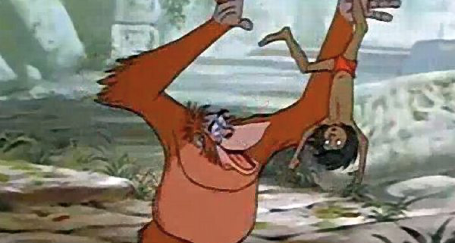 Un orang-outan animé joyeusement suspendu la tête en bas à une vigne de la jungle, agitant une main et tenant un fruit dans l'autre, rappelant une scène du "Livre de la Jungle" de Disney.