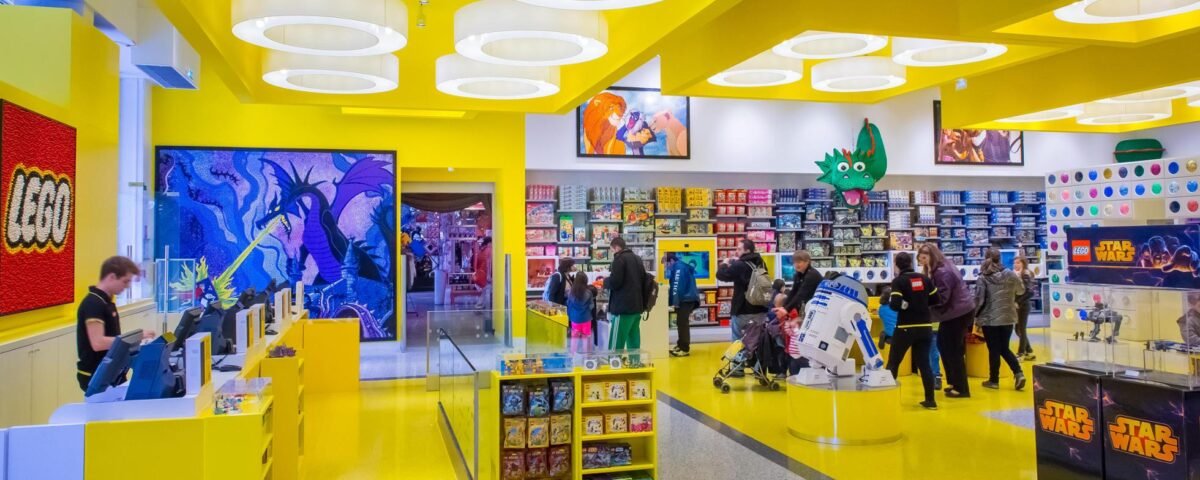 Un magasin Lego à Disney Village avec des murs jaunes et des gens qui se promènent.