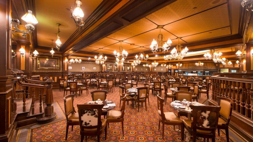 Une salle à manger ornée à Disneyland Paris avec des lustres et des tables.