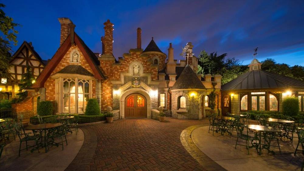 Le restaurant Toad Hall de Disneyland Paris présente un bâtiment en brique avec une allée ronde et une passerelle en pierre.