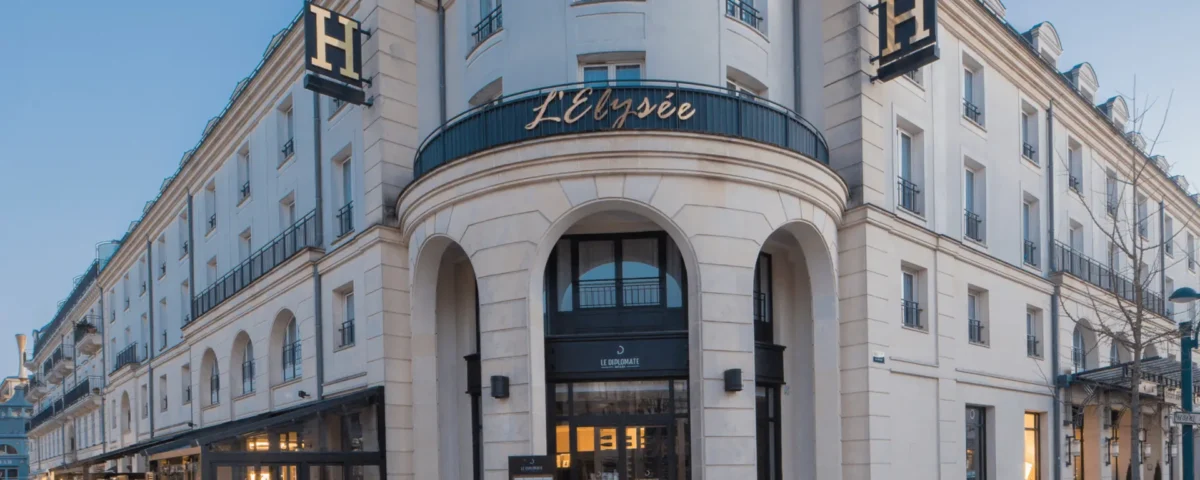 Vue extérieure du bâtiment incurvé surmonté de l'enseigne "Elysée Val d'Europe", mettant en valeur l'architecture classique et le design élégant, situé au coin d'une rue, sous un ciel dégagé