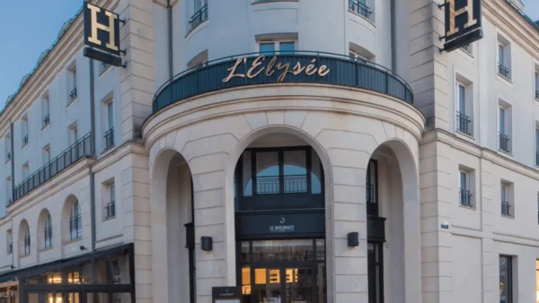 Vue extérieure du bâtiment incurvé surmonté de l'enseigne "Elysée Val d'Europe", mettant en valeur l'architecture classique et le design élégant, situé au coin d'une rue, sous un ciel dégagé