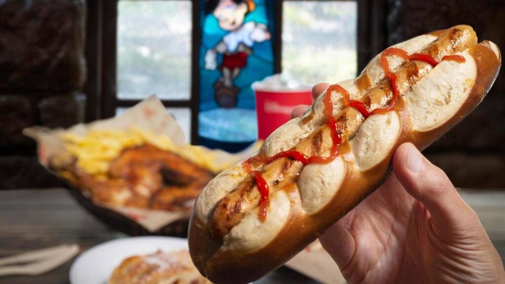 Une personne tient un hot-dog avec du ketchup dessus à Disneyland Paris.