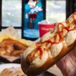 Une personne tient un hot-dog avec du ketchup dessus à Disneyland Paris.