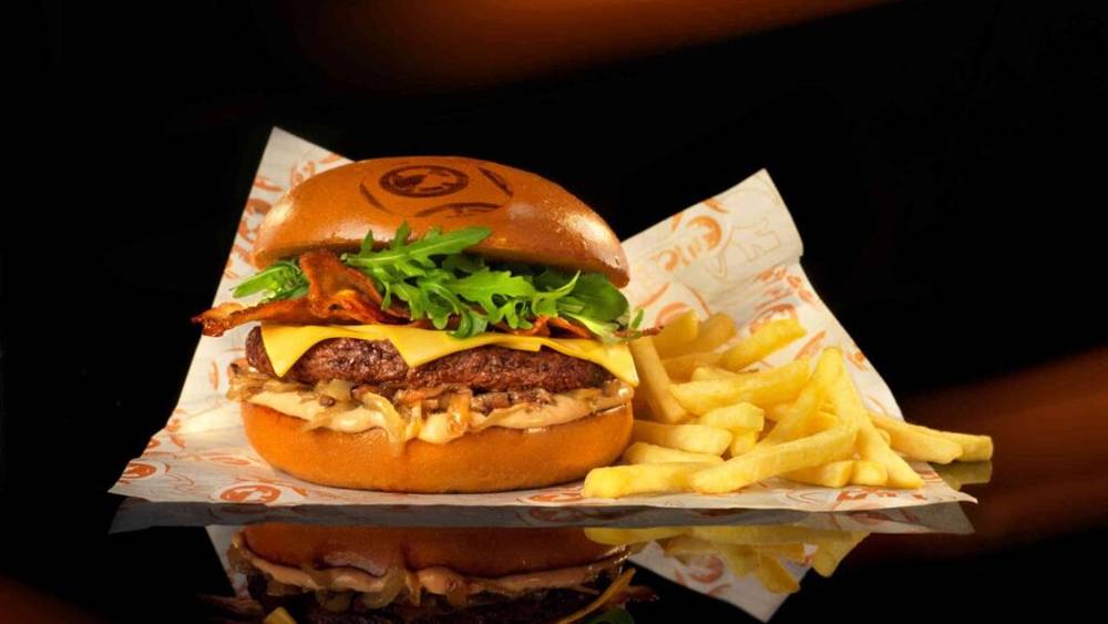 Un burger du Café Hyperion accompagné de frites et de ketchup sur une serviette, dégusté à Disneyland Paris.