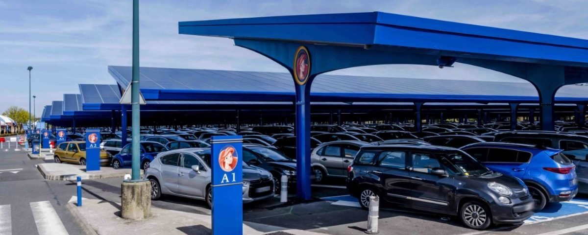 Un parking avec de nombreuses voitures garées sous un auvent bleu, disponible pour stationner à Disneyland Paris à des horaires précis.