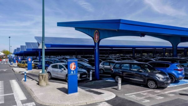 Un parking avec de nombreuses voitures garées sous un auvent bleu, disponible pour stationner à Disneyland Paris à des horaires précis.