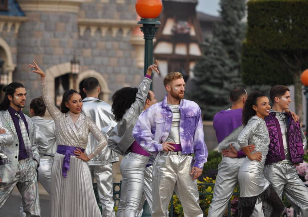 Un groupe de personnes vêtues de tenues argentées posant devant un château à Disneyland Paris.