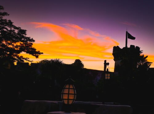 Un coucher de soleil coloré avec un château en arrière-plan à Disneyland Paris.