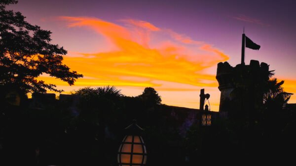 Un coucher de soleil coloré avec un château en arrière-plan à Disneyland Paris.