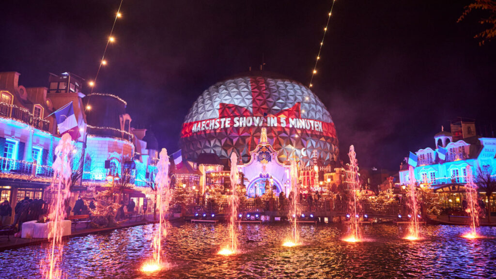 Une fontaine devant un immeuble la nuit à Disneyland Paris.