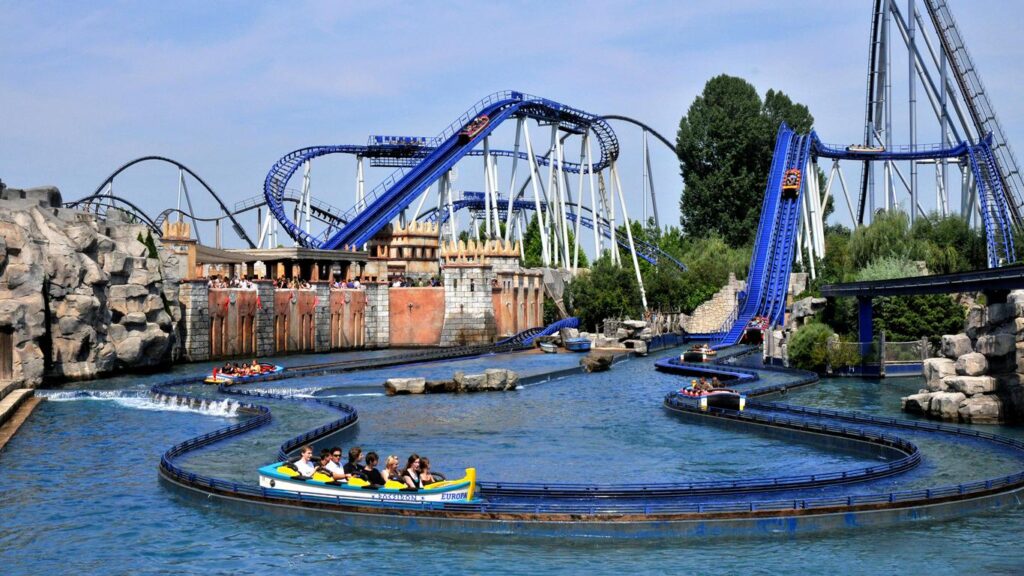 Un parc d'attractions avec des montagnes russes et un manège aquatique, semblable à Disneyland Paris.