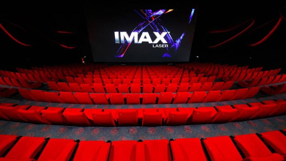 Une salle avec des sièges rouges et un écran indiquant imax, située dans un cinéma Gaumont.